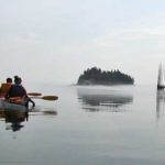 Two Kayakers Heading Out onto the Misty Bay of Fundy with an Island and Fishing Weir in the Background, New Brunswick